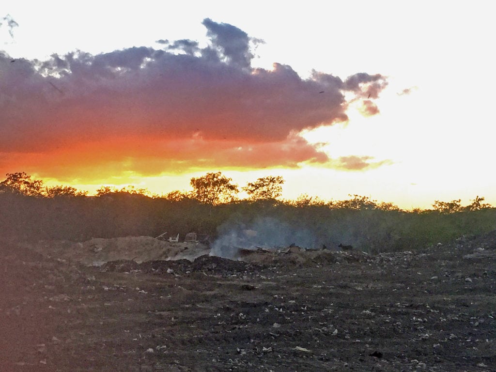 A fire burns near car tires.