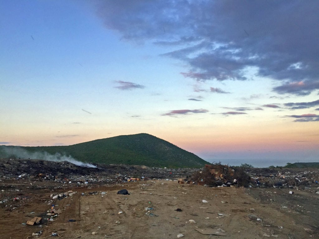 The bulldozer has been razing the landfill, though spots still smoulder.